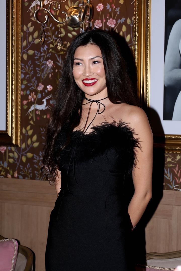 Черное бандажное платье с перьями облегает фигуру делая ее точенным тянется